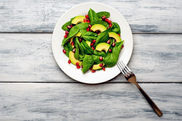 Salat mit Avocado, Rucola, Spinat, Granatapfel, Samen auf Holzhintergrund