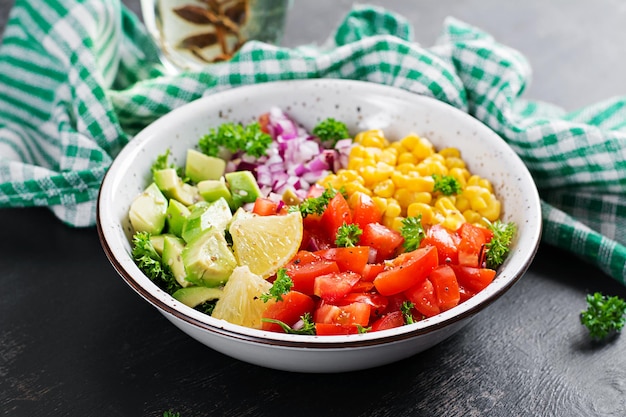 Salat mit Avocado, Tomaten, roten Zwiebeln und Mais in einer Schüssel. Vegetarische Buddha-Schüssel. Veganes Essen.