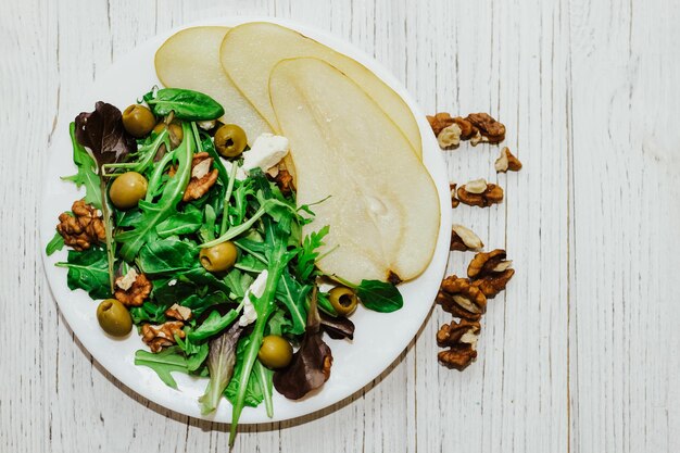 Salat mit Birnen-Kräuter-Rucola-Prosciutto-Käse, grünen Oliven und Nüssen