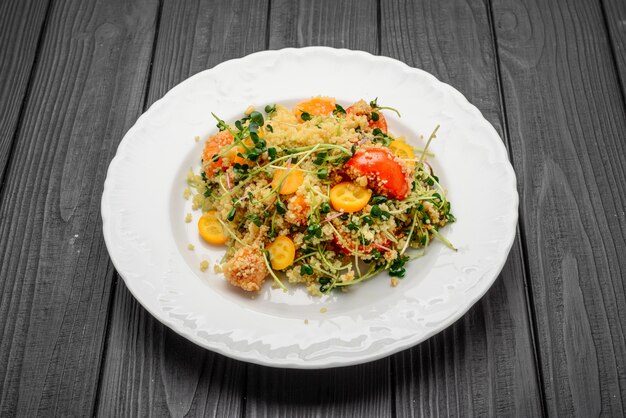 Salat mit Bulgur und Gemüse, Tabouleh, auf dunklem Holz. Tönung.