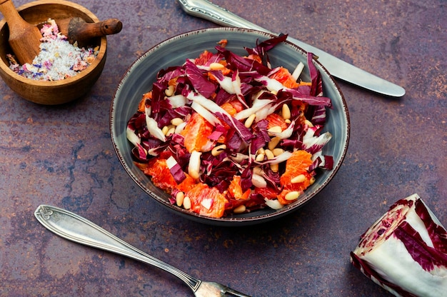 Salat mit Chicorée und orangefarbenem Holztisch