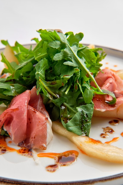 Salat mit dem jamon, Birne und Arugula getrennt auf Weiß