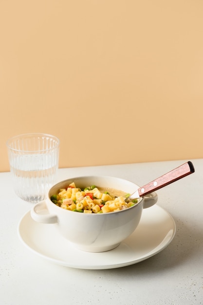 Salat mit Ditalini-Nudeln, Erbsen, veganer Wurst auf modernem weißen Tisch. Nahansicht.