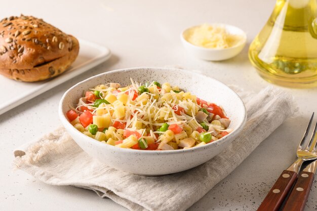 Salat mit Ditalini-Nudeln, Erbsen, veganer Wurst auf modernem weißen Tisch. Nahansicht.