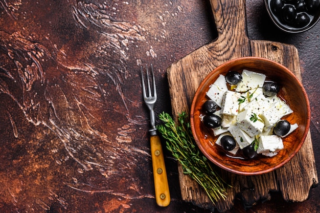 Salat mit frischem Fetakäse, Thymian und Oliven. Dunkler Hintergrund.