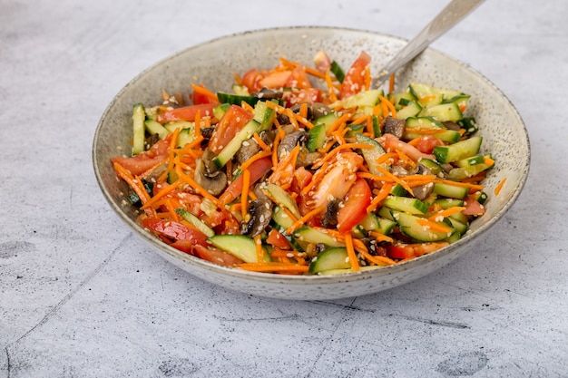 Salat mit frischem Gemüse, in einem Teller mischen, auf grauem Hintergrund, Ansicht von oben