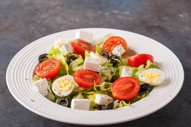 Salat mit frischem Gemüse: Tomaten, Wachteleier, Salat, Käse und schwarze Oliven. Diät und gesundes Lebensmittelkonzept.