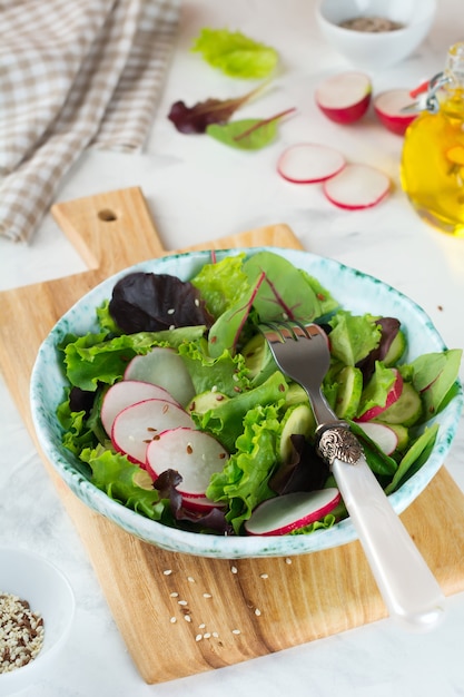 Salat mit frischen Radieschen, Rucola, Rüben, Mangold, Sonnenblumenkernen, Leinsamen und Sesam auf hellem Hintergrund