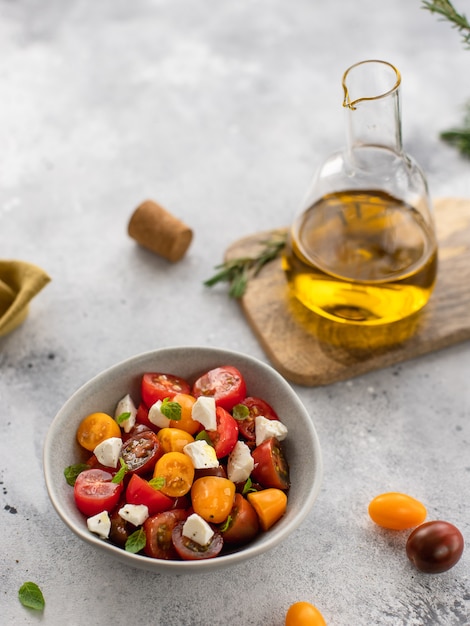 Salat mit frischen Tomaten, Feta-Käse, Basilikum, Olivenöl vegitarian gesundes Konzept graue Oberfläche,