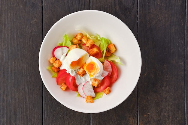 Salat mit frischen Tomaten in der Nähe von Radieschen und gekochtem Ei