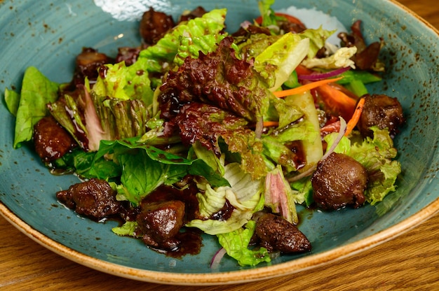 Salat mit gebratenen Pilzen, Tomaten und Salat auf einem Holztisch, Draufsicht