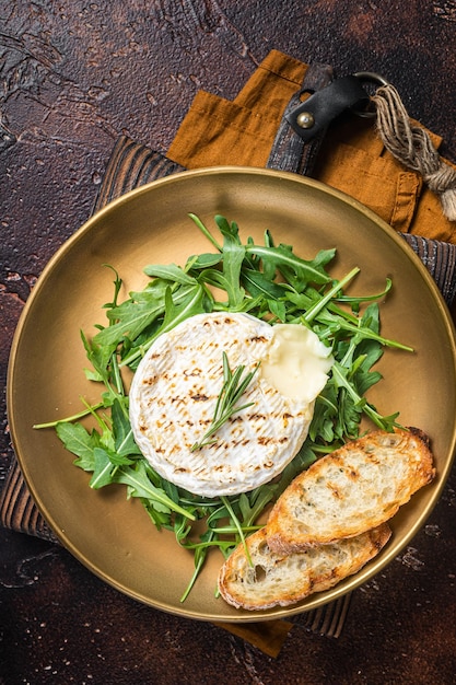 Salat mit gegrilltem Camembert-Käse-Rucola-Toast und Rosmarin in einem Teller Dunkler Hintergrund Draufsicht