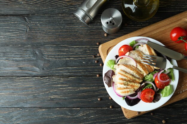 Salat mit gegrilltem Hähnchen auf Holztisch