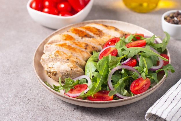 Salat mit gegrilltem Hähnchen, frischem Gemüse, Spinat, Ruccola, roten Zwiebeln und Tomaten.