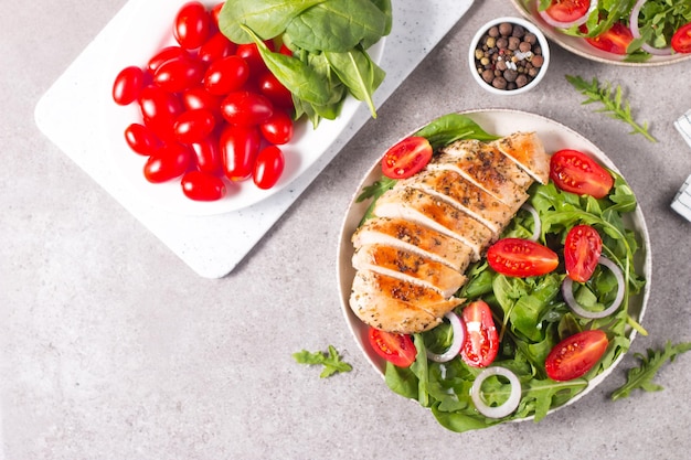 Salat mit gegrilltem Hähnchenfiletfleisch, frischem Gemüse, Spinat, Ruccola, roten Zwiebeln und Tomaten.