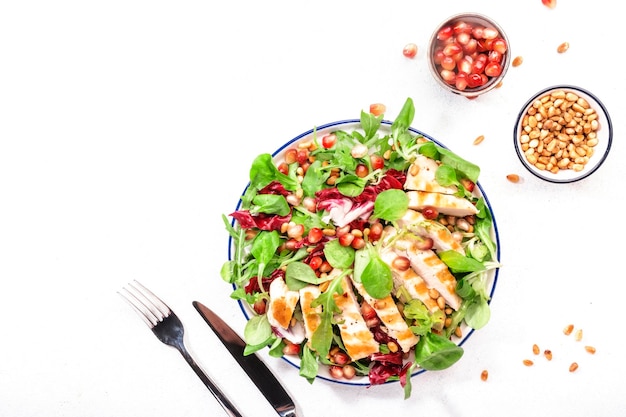 Salat mit gegrilltem Hühnerspinat Rucola Zedernnüsse und Granatapfelkerne Gesundes Essen und Esskonzept Draufsicht Blauer Hintergrund