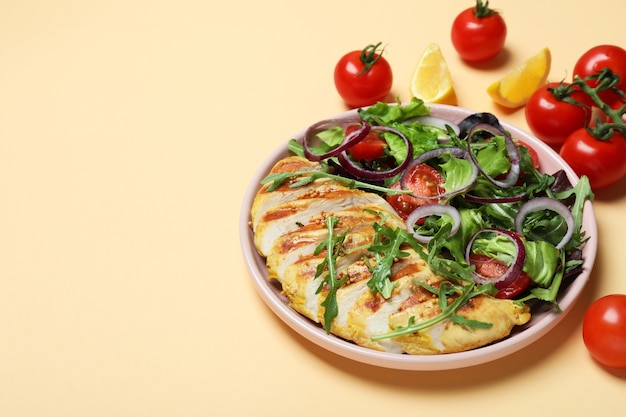 Salat mit gegrilltem Huhn und Zutaten auf beigem Hintergrund