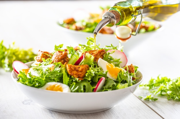 Salat mit gemischten Zutaten Stücke von Hühnerbrustei und Rettich. Olivenöl in Salat gießen.