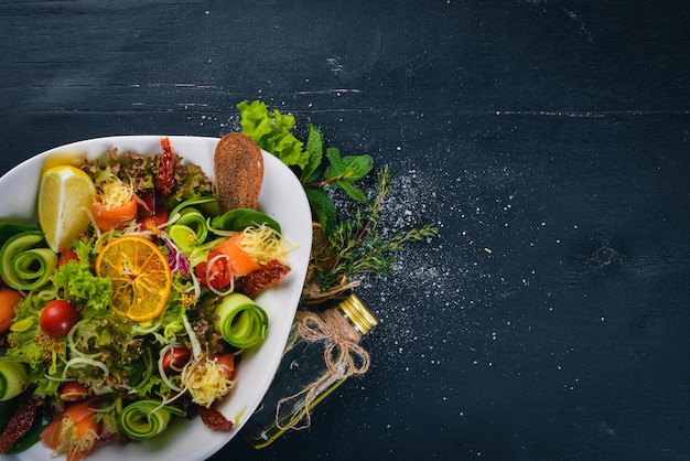 Salat mit gesalzenem Lachskäse und Salatblättern auf einer Holzoberfläche Draufsicht Freier Platz für Ihren Text