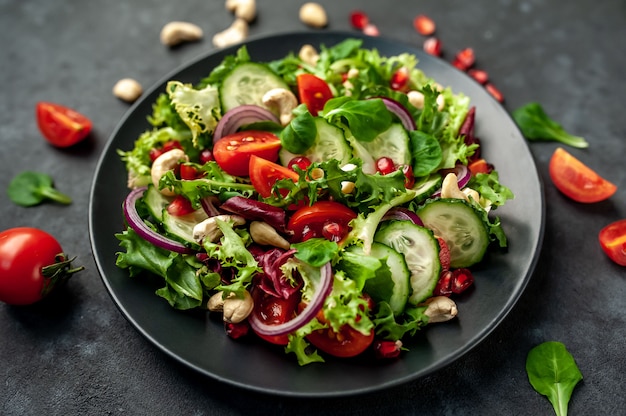 Salat mit Granatapfel, Tomaten, frischen Gurken, Zwiebeln, Sesam und Cashewnüssen