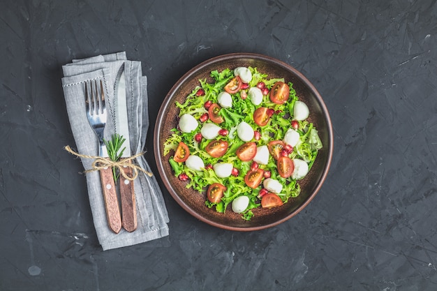 Salat mit grüner Salatmischung serviert auf einer braunen Keramikplatte