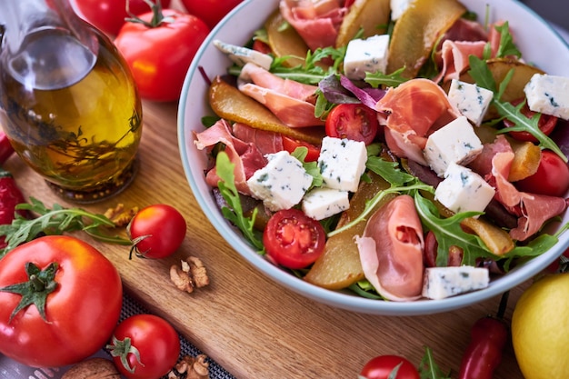 Salat mit Jamon oder Prosciutto Birnen Tomaten und Rucola auf Holzbrett