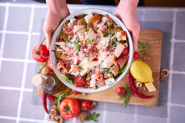 Salat mit Jamon oder Prosciutto Birnen Tomaten und Rucola auf Holzbrett