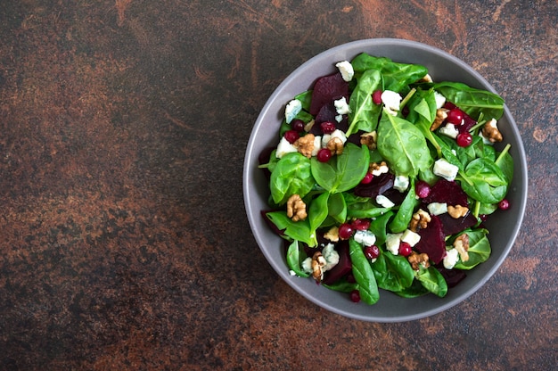 Salat mit jungem Spinat, gekochten Rüben, Blauschimmelkäse, Nüssen, Preiselbeeren in einer Schüssel. Leckeres Diät-Fitnessgericht. Vitaminsalat. Richtige Ernährung. Draufsicht.