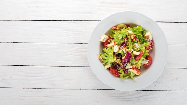 Salat mit Käse, Nüssen und frischem Gemüse Auf einem hölzernen Hintergrund Ansicht von oben Kopieren Sie Platz für Ihren Text