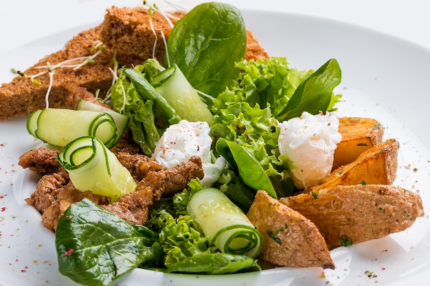 Salat mit Kartoffelcroutons, Ei und Kräutern auf einem weißen Teller