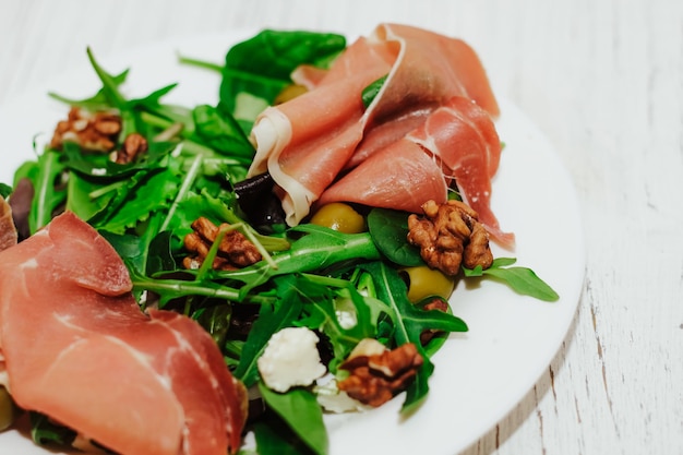 Salat mit Kräuter-Rucola-Prosciutto-Käse, grünen Oliven und Nüssen