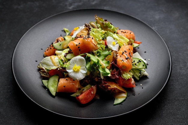 Salat mit Lachs auf einem dunklen Teller