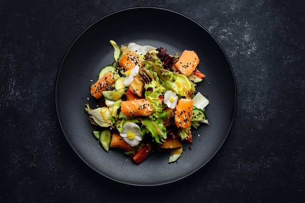 Salat mit Lachs auf einem dunklen Teller