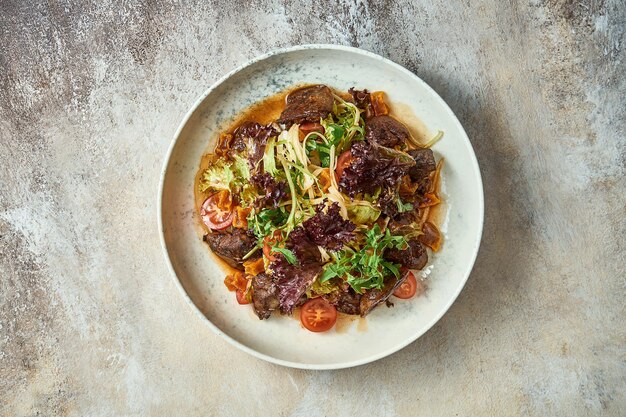 Salat mit Leber und Gemüse in einer Platte. Nahaufnahme, selektiver Fokus.