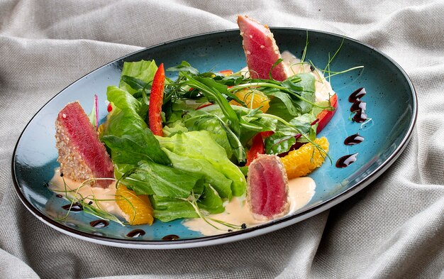 Salat mit Orange und Thunfisch auf Textilhintergrund