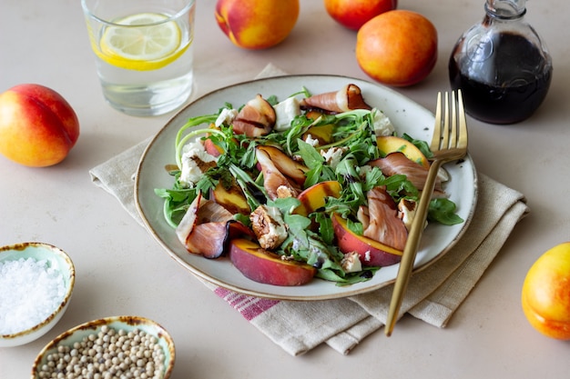 Salat mit Pfirsichen, Rucola, Käse und Jamon. Gesundes Essen.