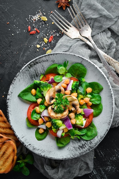 Salat mit Pilzen, Spinat, türkische Erbsen und Zwiebeln in einem Teller auf Holzhintergrund Draufsicht Freier Platz für Ihren Text Flach lag