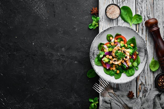 Salat mit Pilzen, Spinat, türkische Erbsen und Zwiebeln in einem Teller auf Holzhintergrund Draufsicht Freier Platz für Ihren Text Flach lag