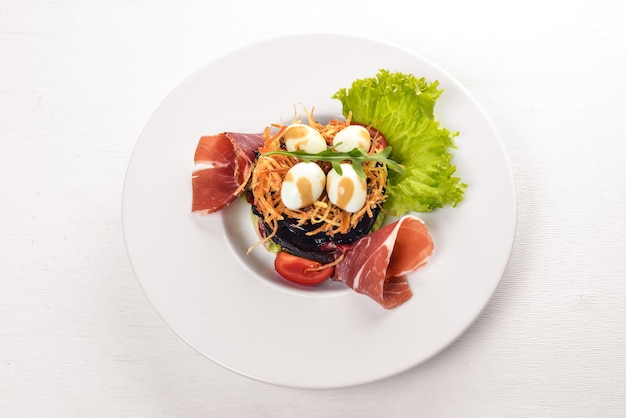 Salat mit Prosciutto Wachteleiern Pflaumen und frischem Gemüse auf dem Teller Auf einem hölzernen Hintergrund Ansicht von oben Freier Platz für Text