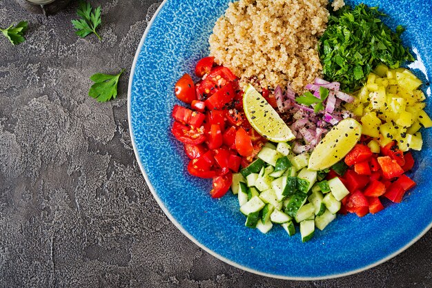 Salat mit Quinoa, Rucola, Gemüsepaprika, Tomaten und Gurken in Schüssel