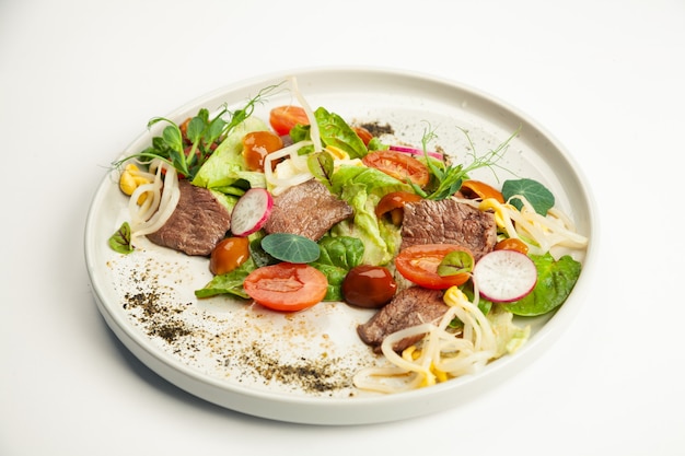 Salat mit Rindfleisch Tataki auf einem Teller.