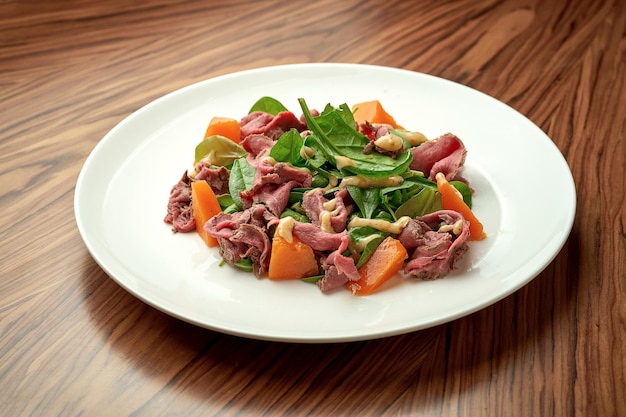 Salat mit Roastbeef und Kürbis in einem weißen Teller.