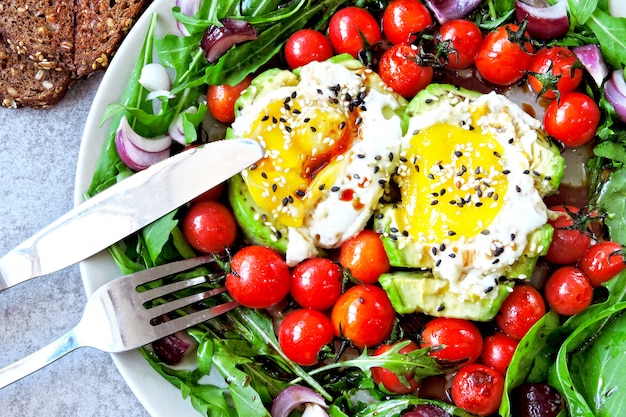 Salat mit Rucola, Avocado, Ei und Kirschtomaten.