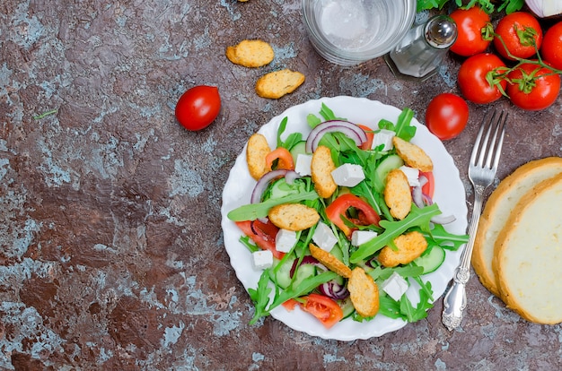 Salat mit Rucola, Käse, Tomaten, Gurken und Crackern