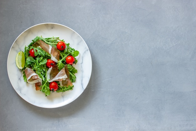 Salat mit Rucola, Tomaten und Schinken.