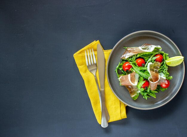 Salat mit Rucola, Tomaten und Schinken.