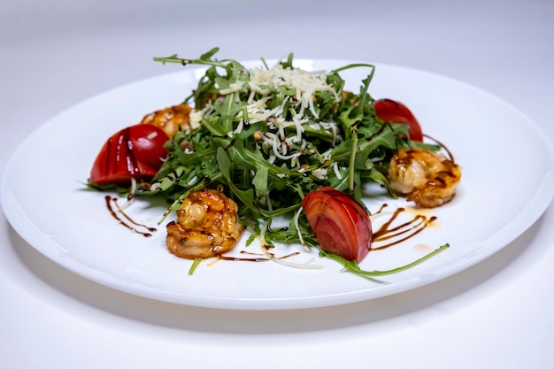 Salat mit Rucola und gegrillten Garnelen auf einem weißen Teller und weißem Hintergrund mediterraner National