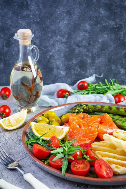 Salat mit Spargel, gegrilltem Halloumi-Käse, Lachsfilet, Tomaten, Rucola und grünen Oliven