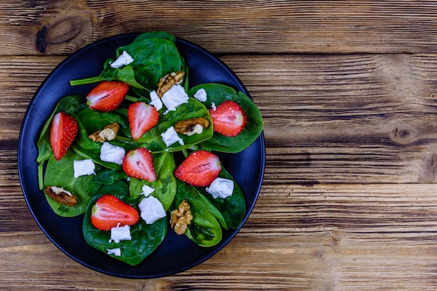 Salat mit Spinatblättern, Feta-Käse, Walnüssen und Erdbeeren auf einer schwarzen Platte Draufsicht