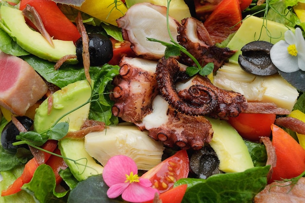 Salat mit Tintenfisch, Thunfisch und Gemüse auf dunklem Hintergrund